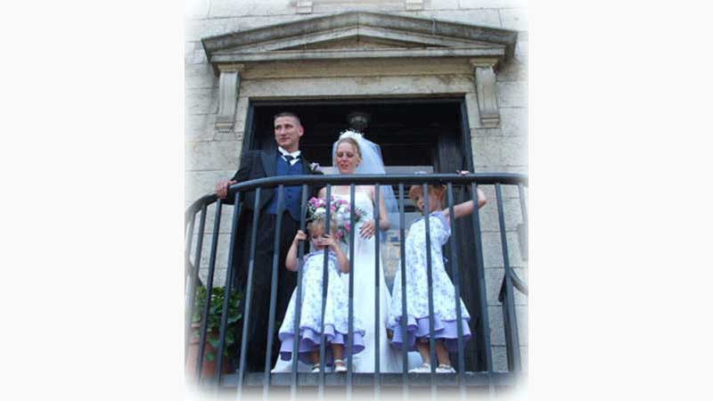 From wedding 2, DJ Kitchener, Bride, Groom and their two small children looking out from an outside balcony with the guests below. they are all dressed beautifully. Taken in Kitchener Ontario